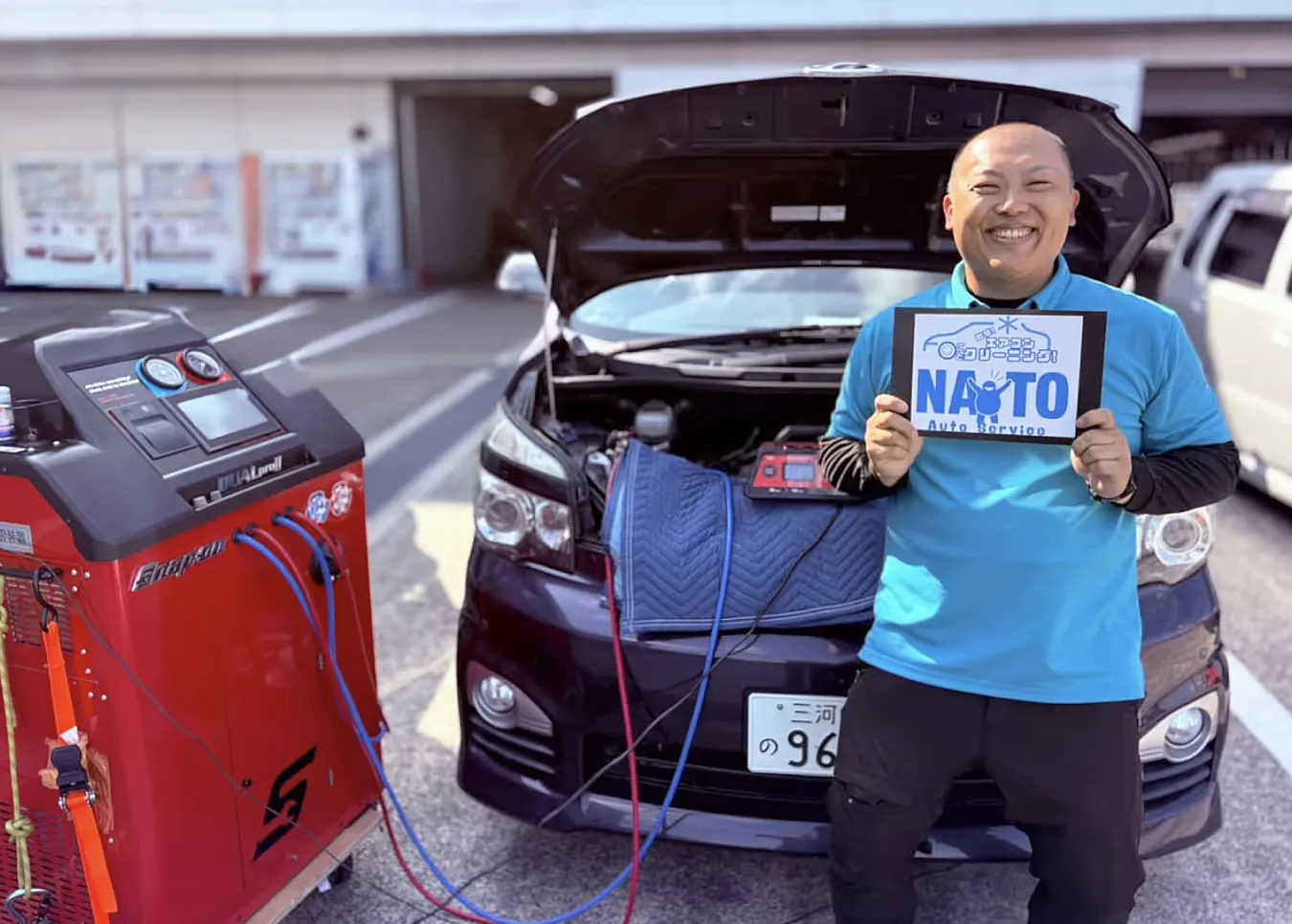 内藤オートサービス代表。出張先でエアコンガスクリーニング機材と施工車両の前で