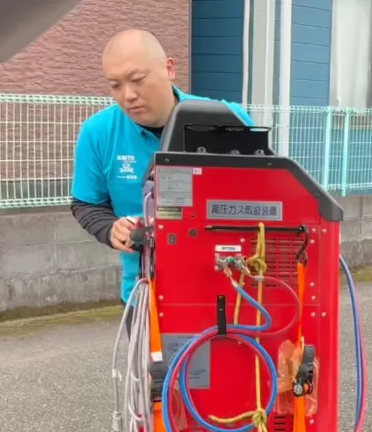 出張先でカーエアコン用の専用機材を操作する内藤オートサービス代表