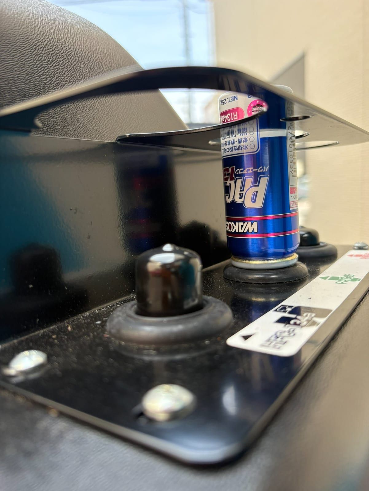 機械の上の受け台に立てて置かれた青い缶